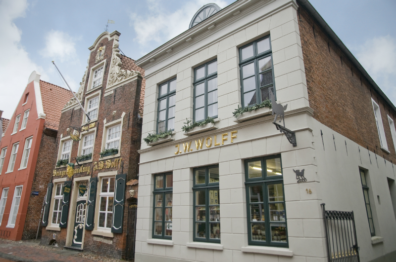 Fassade des historischen Gebäudes J.W. Wolff mit traditioneller Backsteinarchitektur und weißem Anbau.