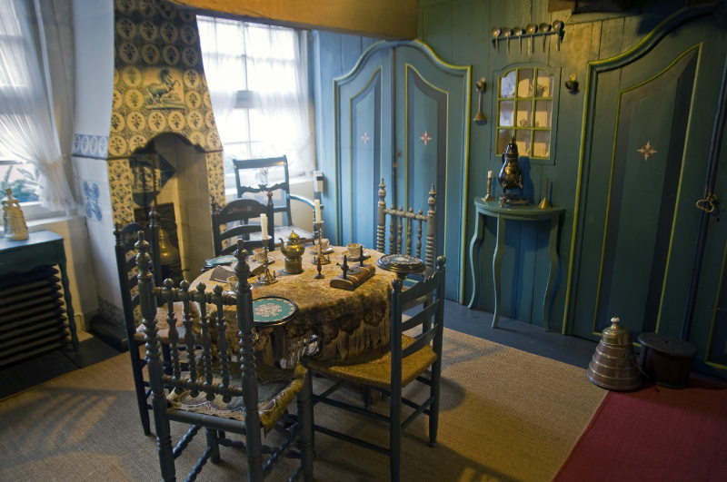 Museum: Ein Essbereich mit grüner Wandvertäfelung, einem dekorierten Tisch, traditionellen Stühlen und einer antiken Einrichtung im friesischen Stil.