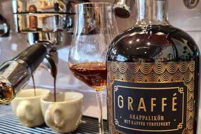 Flasche Graffe vor einer Siebträgermaschine mit einem Grappa-Glas